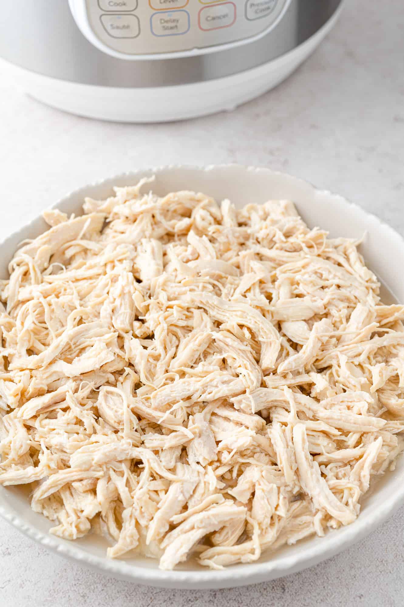 Instant Pot shredded chicken in a large white bowl.