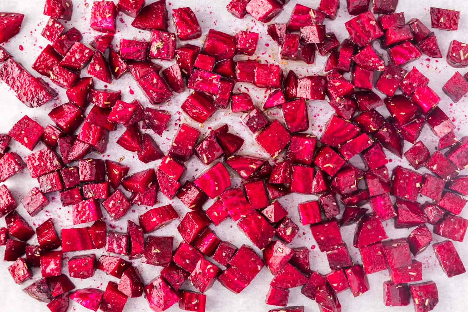 Uncooked diced beets on a sheet pan, ready to be roasted.