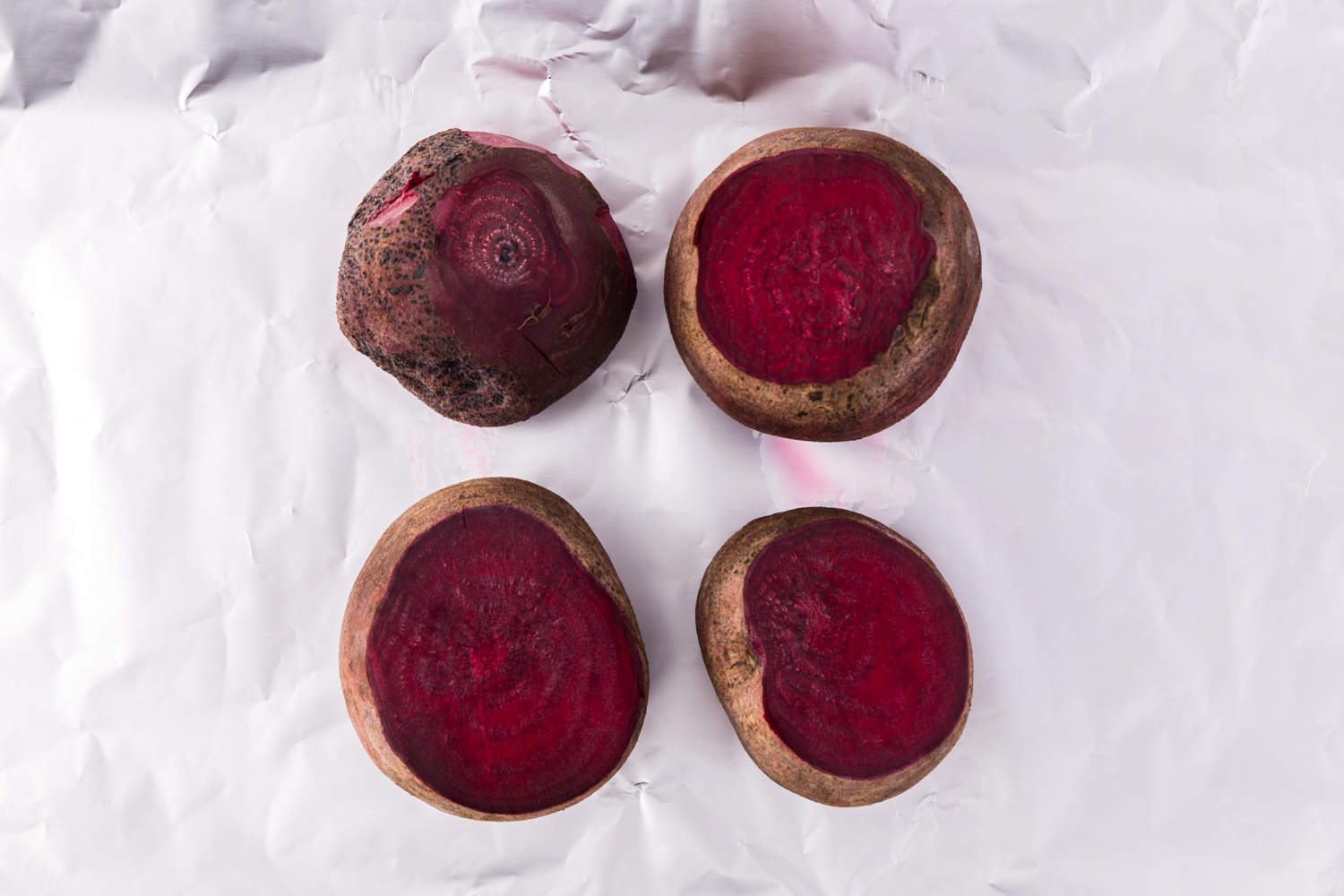 Uncooked beets, sitting on a sheet of foil.