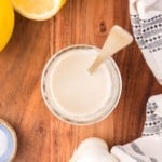 Overhead view of tahini sauce in a small jar, with a spoon.