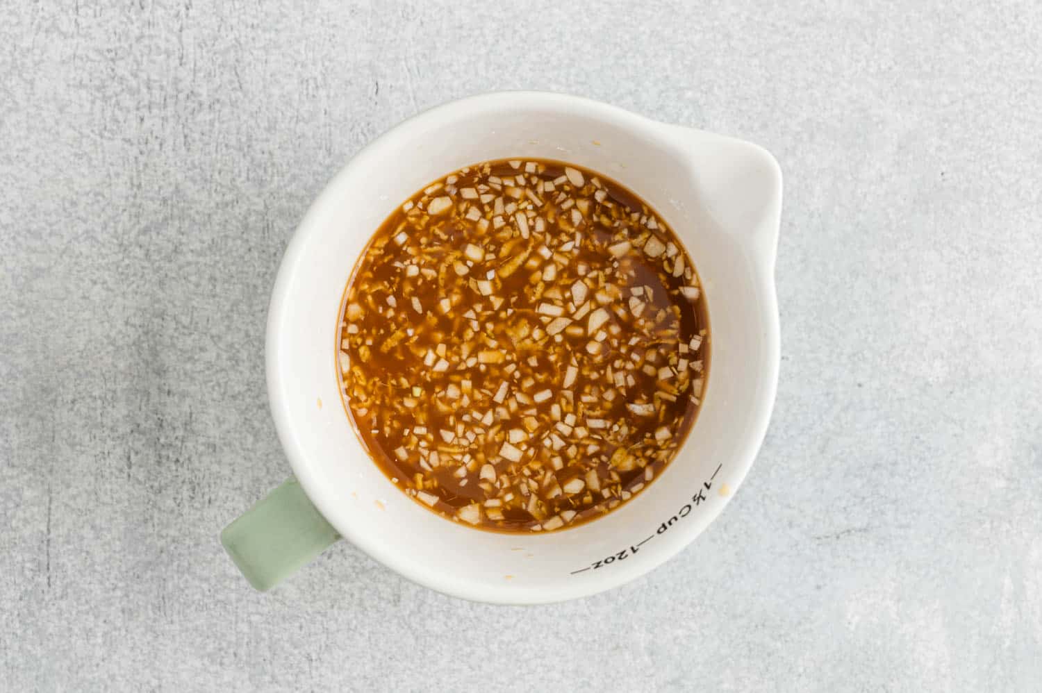 Teriyaki sauce ingredients mixed together in white measuring cup.
