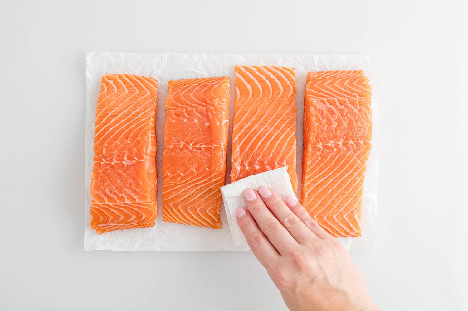 Salmon being patted dry with paper towels.