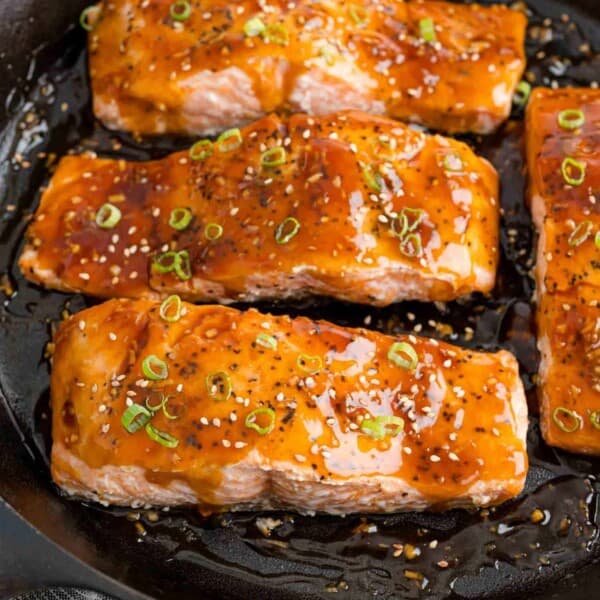 Teriyaki salmon in a black frying pan.