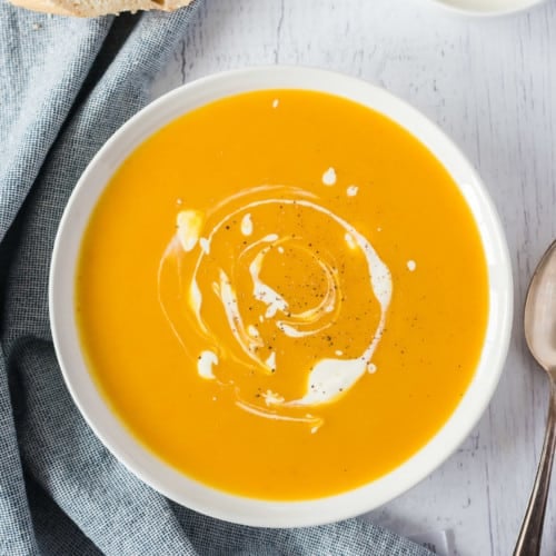 Overhead view of a bowl of slow cooker pumpkin soup swirled with cream.