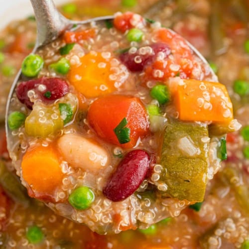 Crockpot minestrone with quinoa, shown in a ladle.