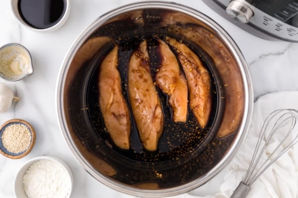 Uncooked chicken coated in teriyaki sauce inside the instant pot.