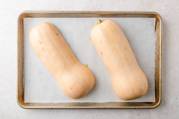 Uncooked squash placed face down on baking sheet.