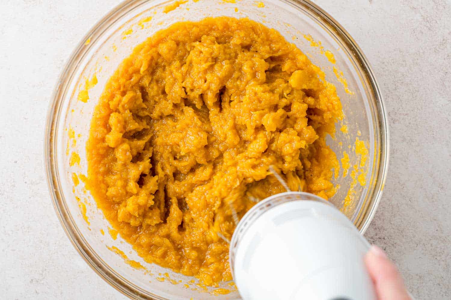 Electric mixer blending butternut squash mash.