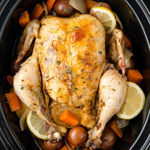 Whole chicken in a crockpot with potatoes and carrots.
