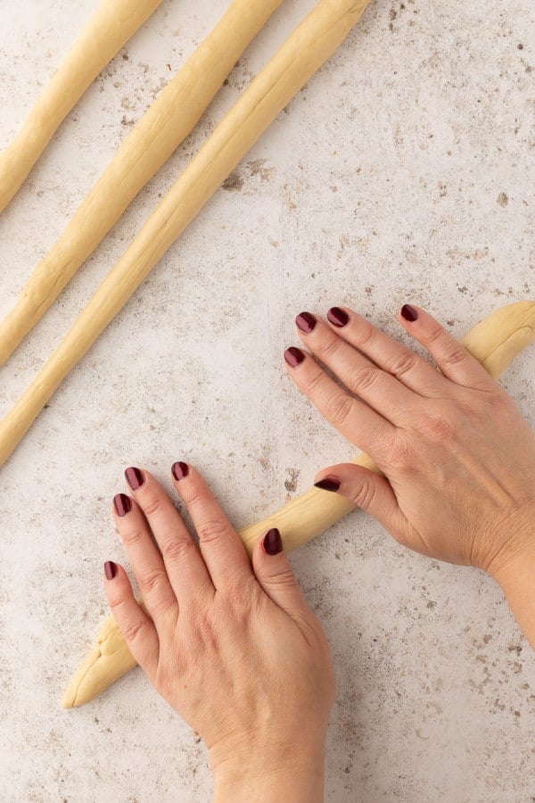 Pretzel dough being rolled into a rope shape.