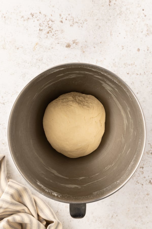 Pretzel dough formed into a ball in a metal mixing bowl.