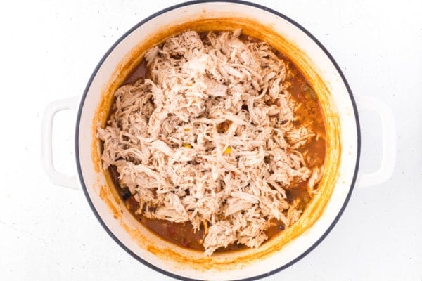 Shredded chicken added to a large pot with the other taco soup ingredients.