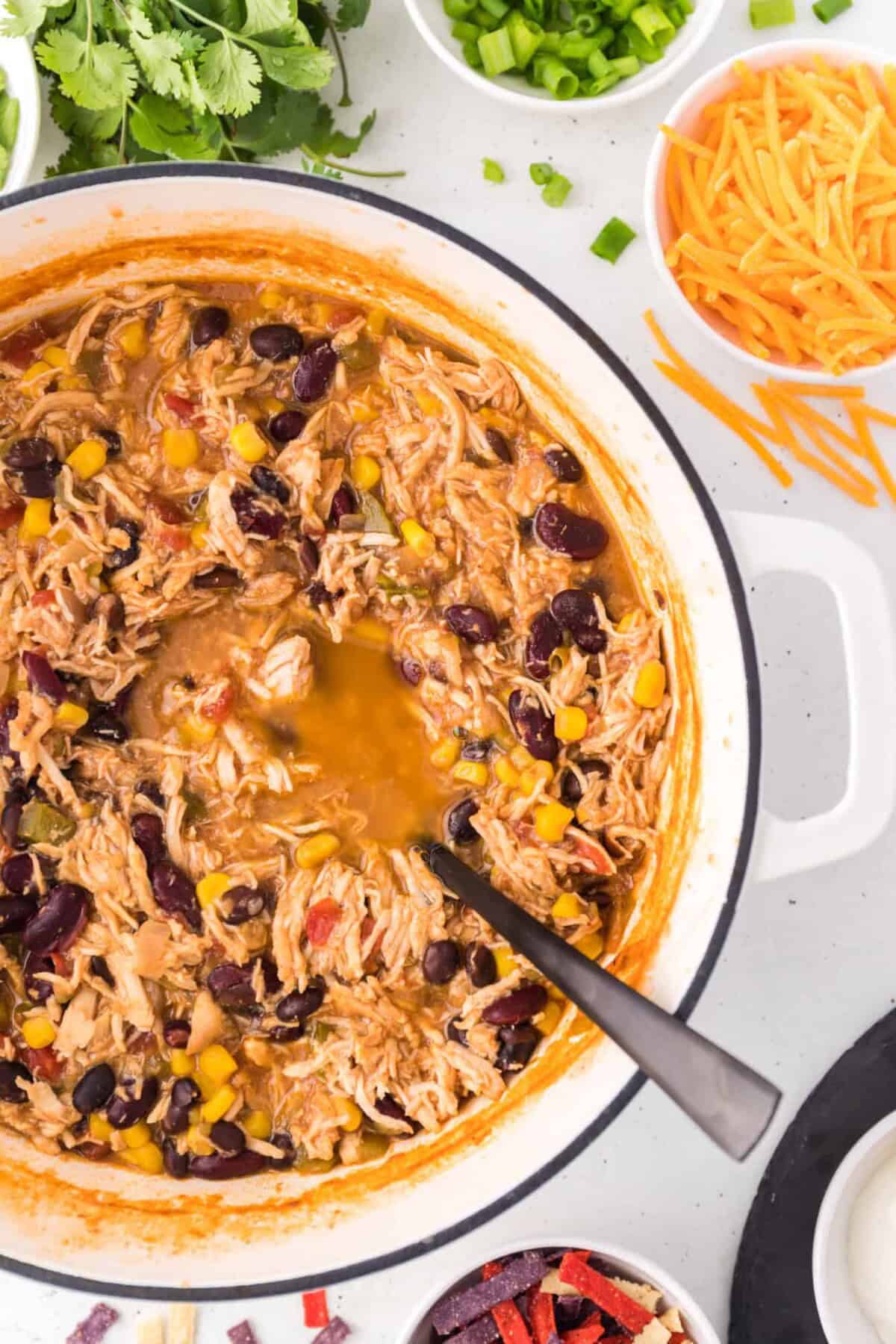 Overhead view of a large pot of chicken taco soup with a serving spoon.