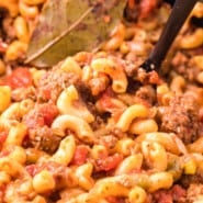 Close up of a serving spoon stuck into goulash inside the crockpot.