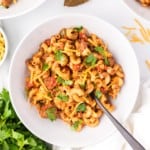 Crockpot goulash in a white bowl with a spoon.