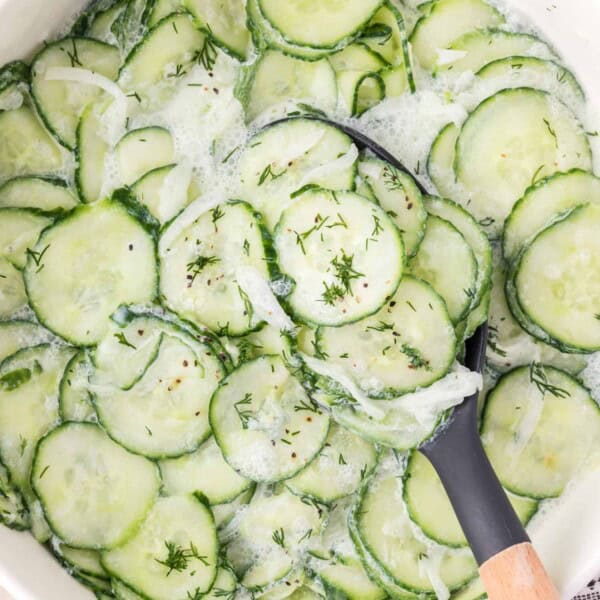 German cucumber salad, with a spoon scooping some out.