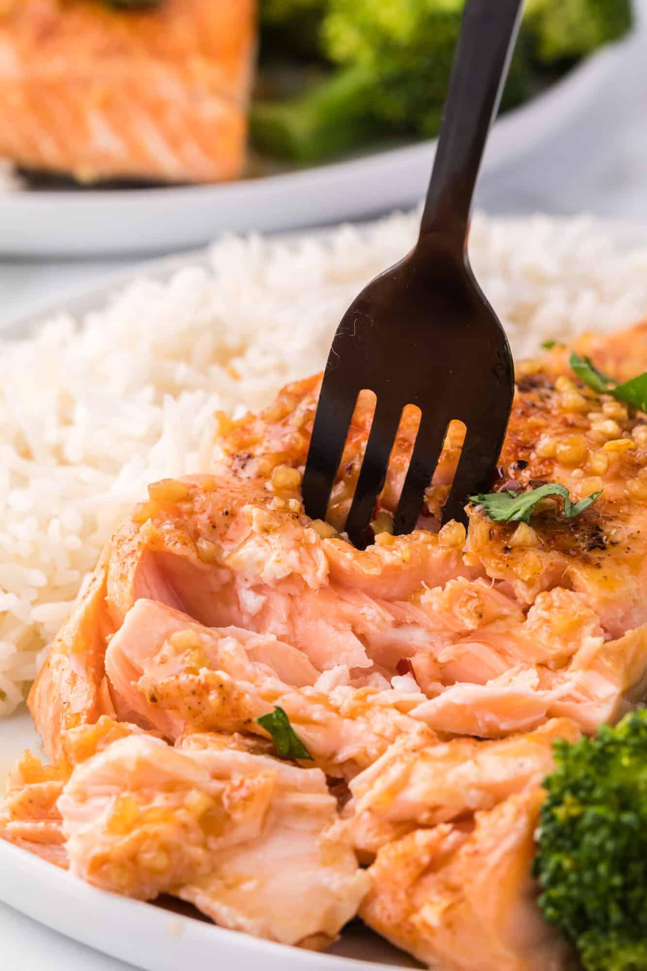 Honey garlic salmon being flaked with a fork.