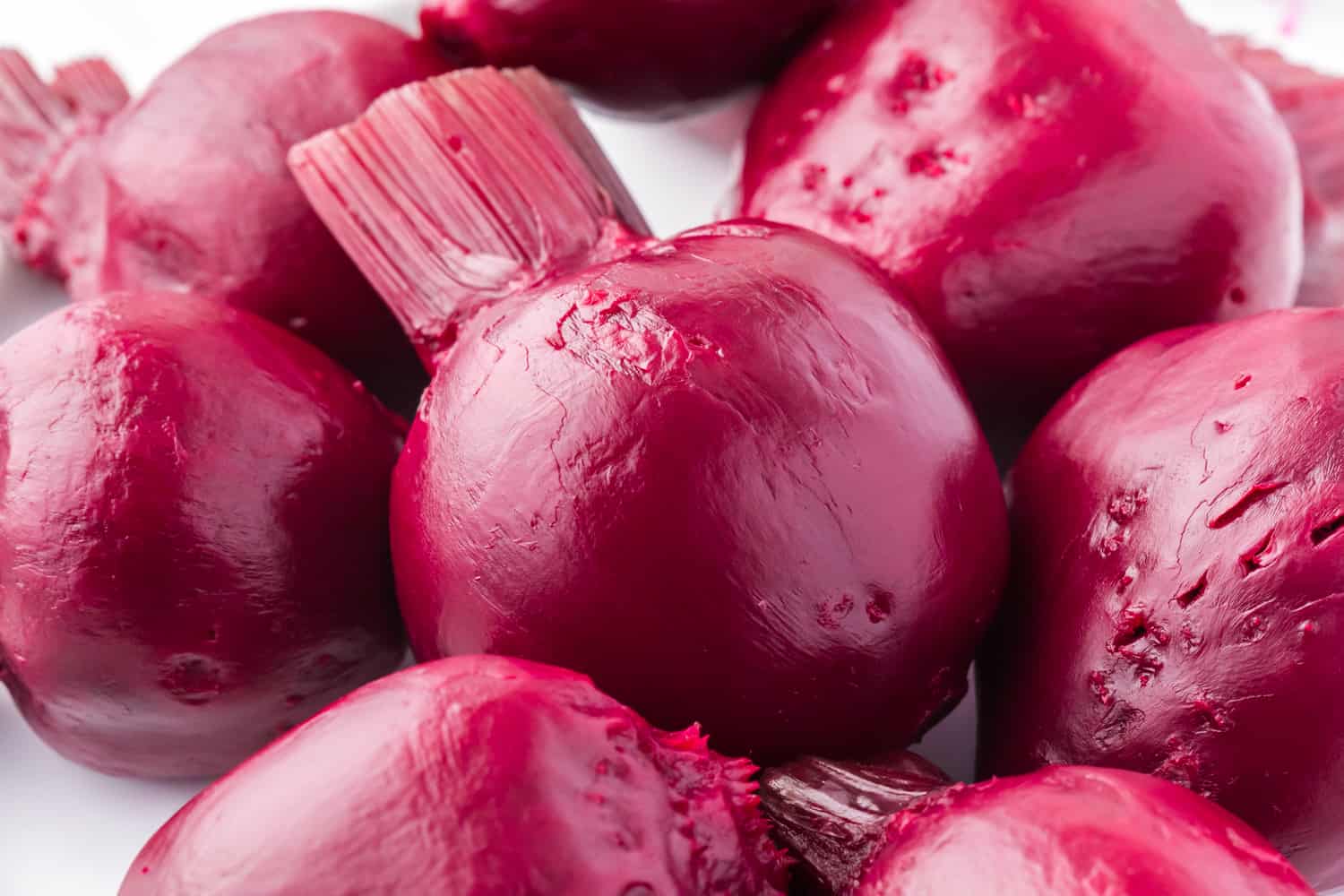 Peeled beets, with just a bit of the greens still attached, now the same color as beets.