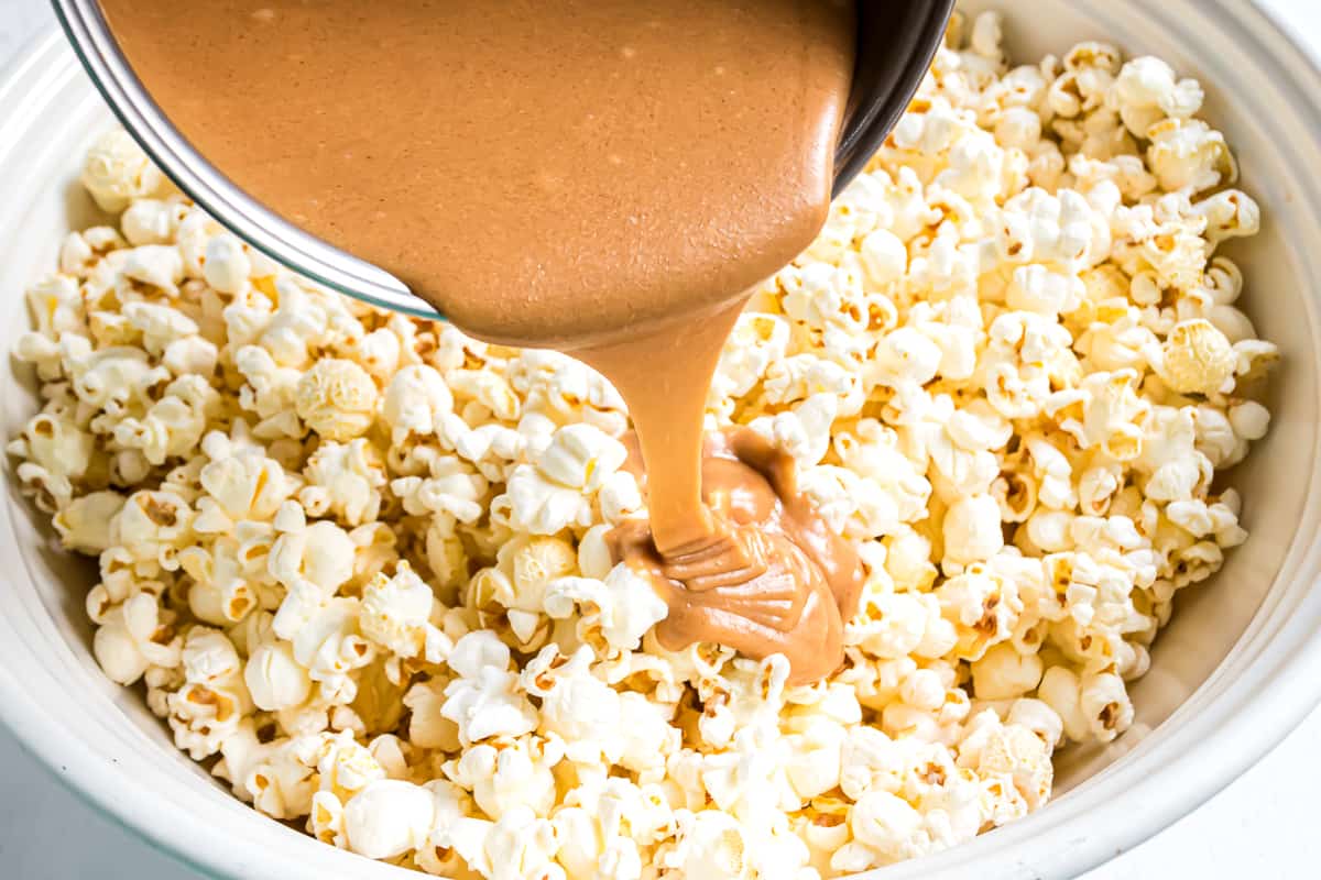 Peanut butter caramel being poured over popcorn.