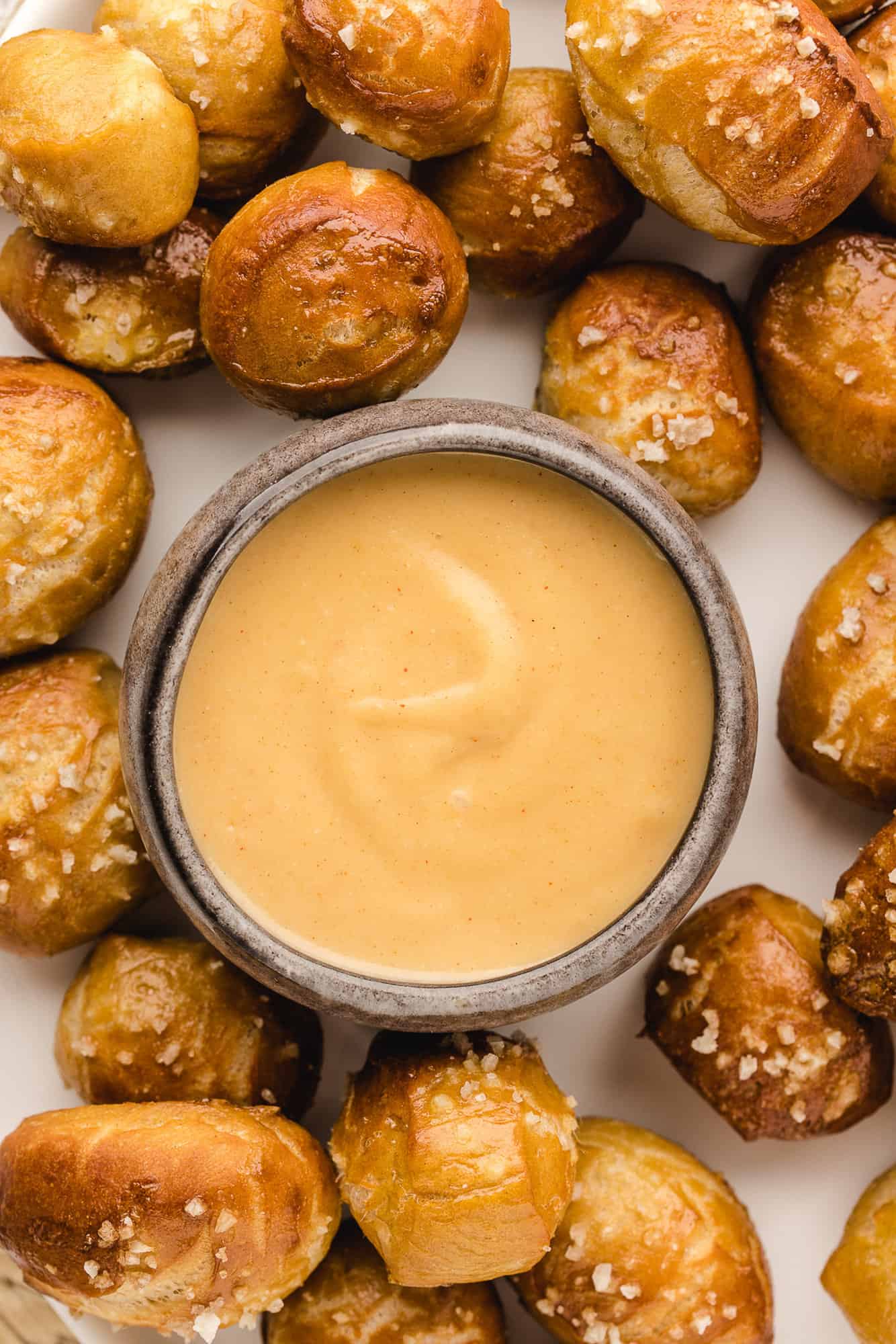 Small bowl of beer cheese dip, surrounded by pretzel bites.