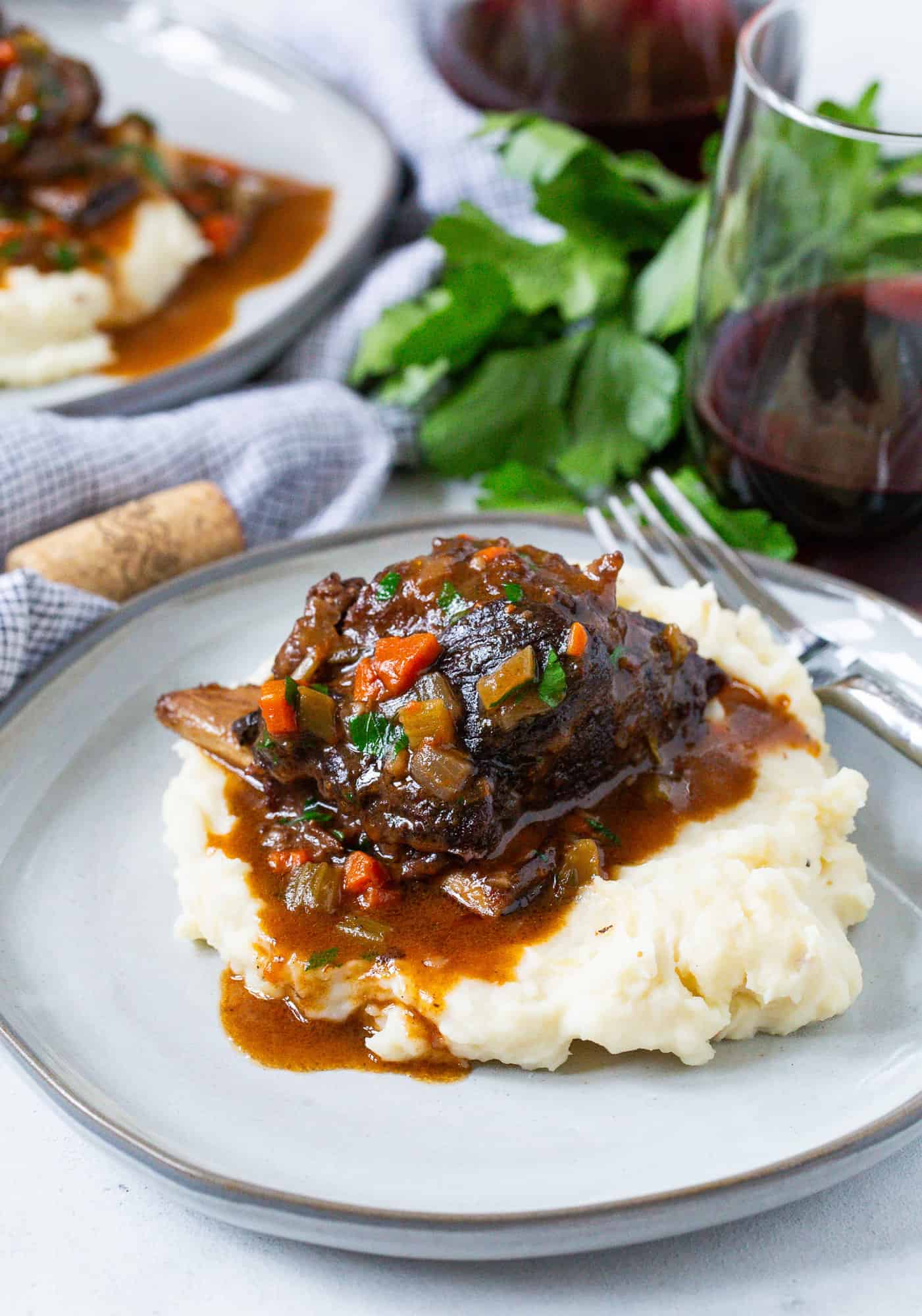 Plate with potatoes and a short rib, topped with gravy.