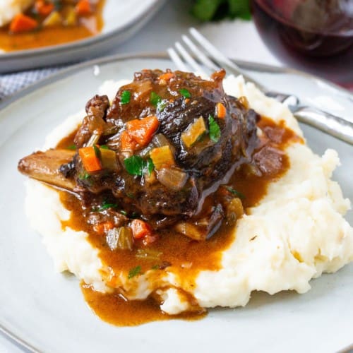 Red wine braised short ribs placed on top of a pile of mashed potatoes.