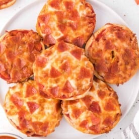 Air fryer bagel bites topped with pepperoni and cheese, on a white plate.