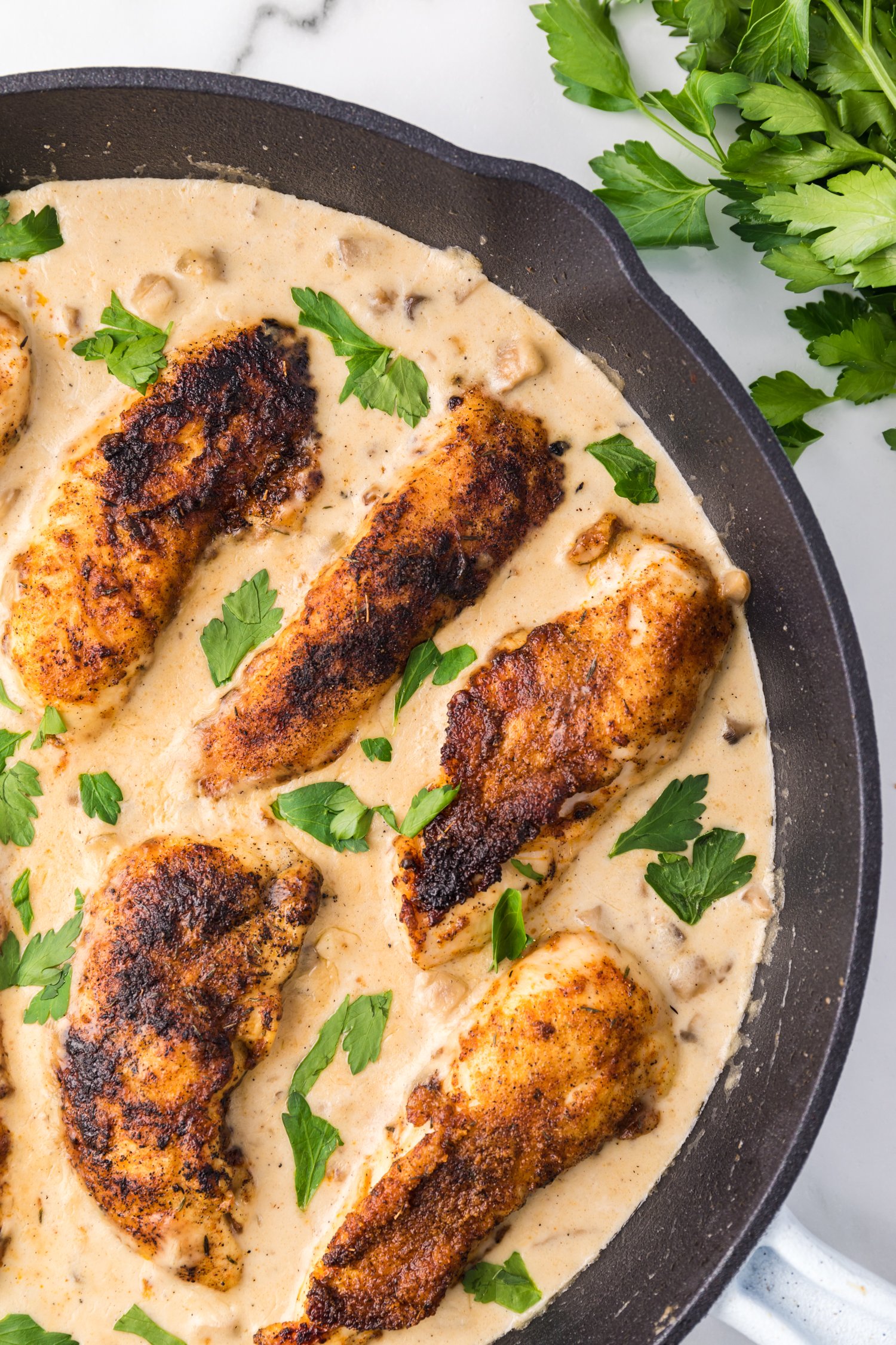 Overhead view of cream of mushroom chicken in a skillet garnished with parsley.