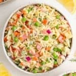 Overhead view of orzo salad with vegetables and a yogurt dill dressing.