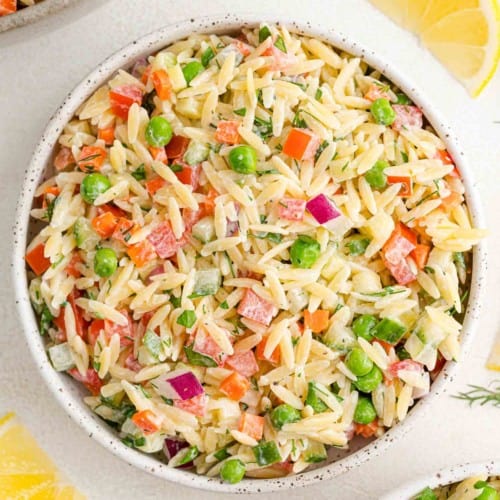 Overhead view of orzo salad with vegetables and a yogurt dill dressing.