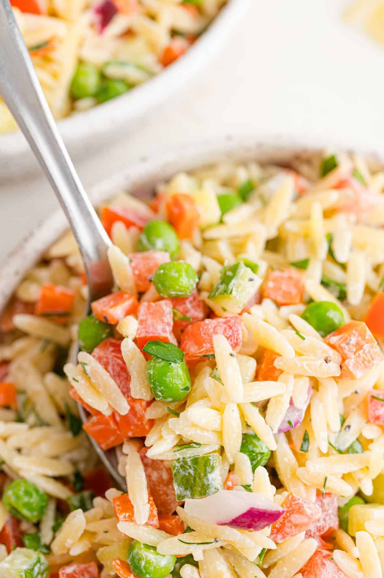 Orzo salad with dill dressing on a serving spoon.