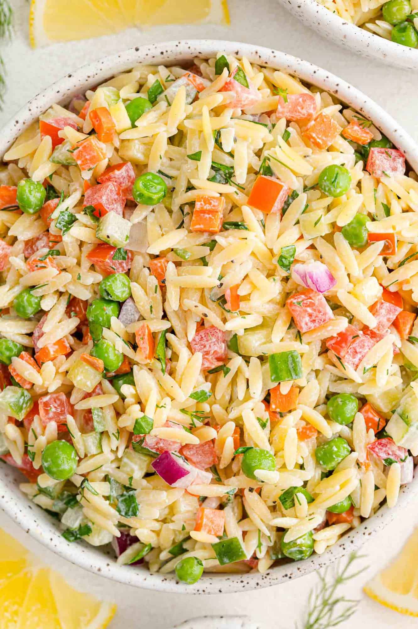 Overhead view of orzo salad with yogurt dill dressing with a variety of vegetables.