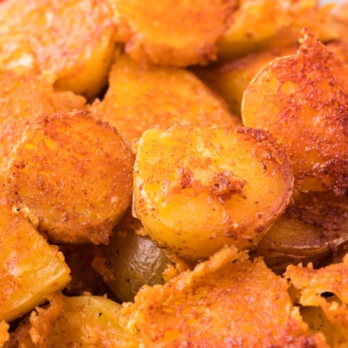 Close up of crispy parmesan potatoes in a white bowl.