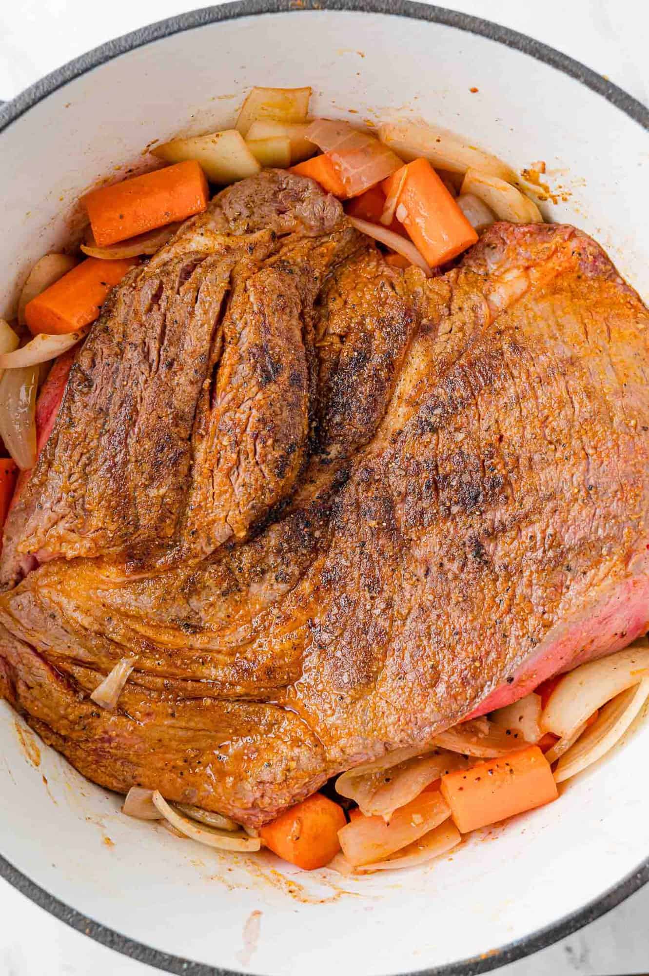 Browned pot roast added to pan with carrots and onions.