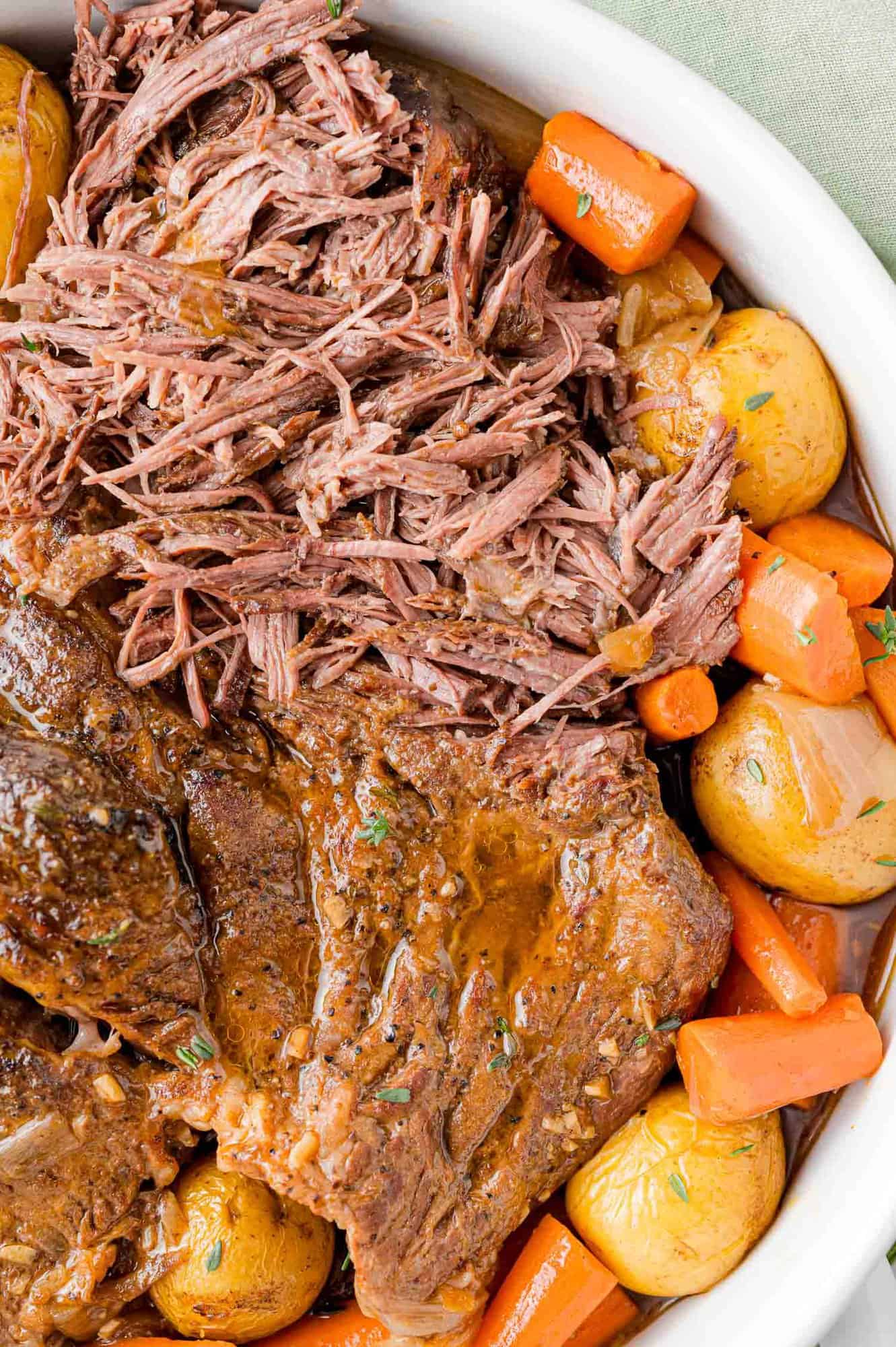 Pot roast, partially shredded, with potatoes and carrots.