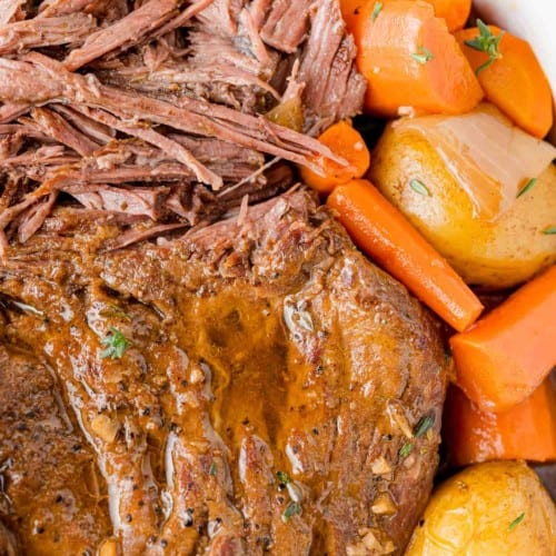 Pot roast, partially shredded, with carrots and potatoes.