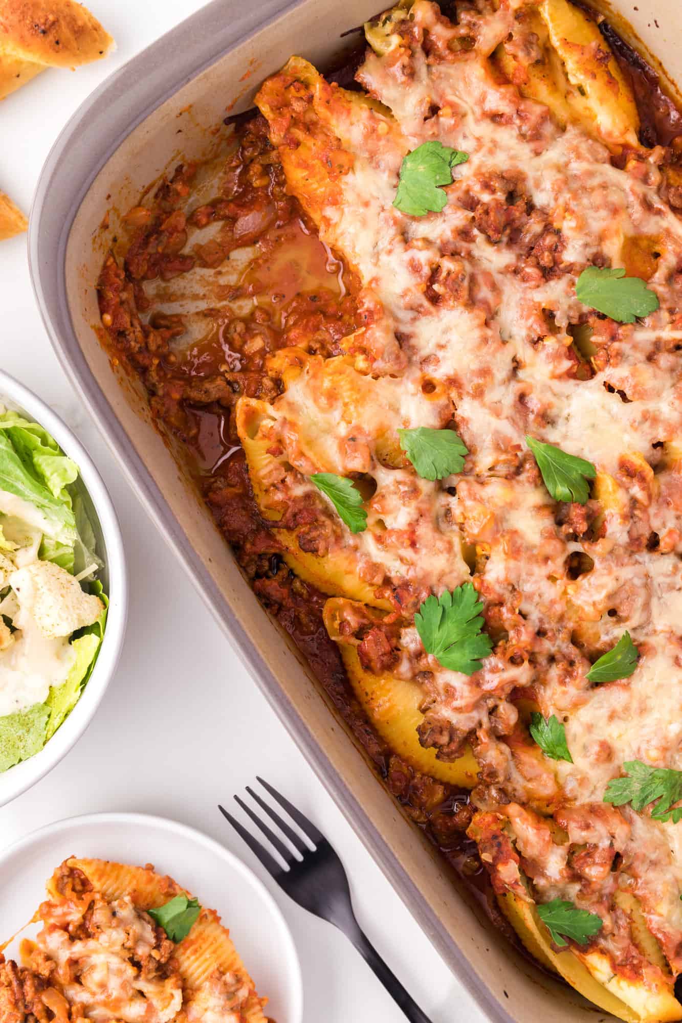 Stuffed shells in a casserole dish, one removed.