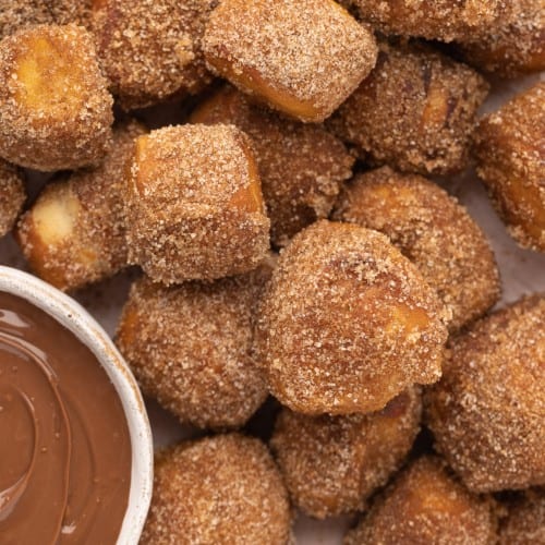 Cinnamon sugar bites with a small bowl of chocolate dip in the corner.