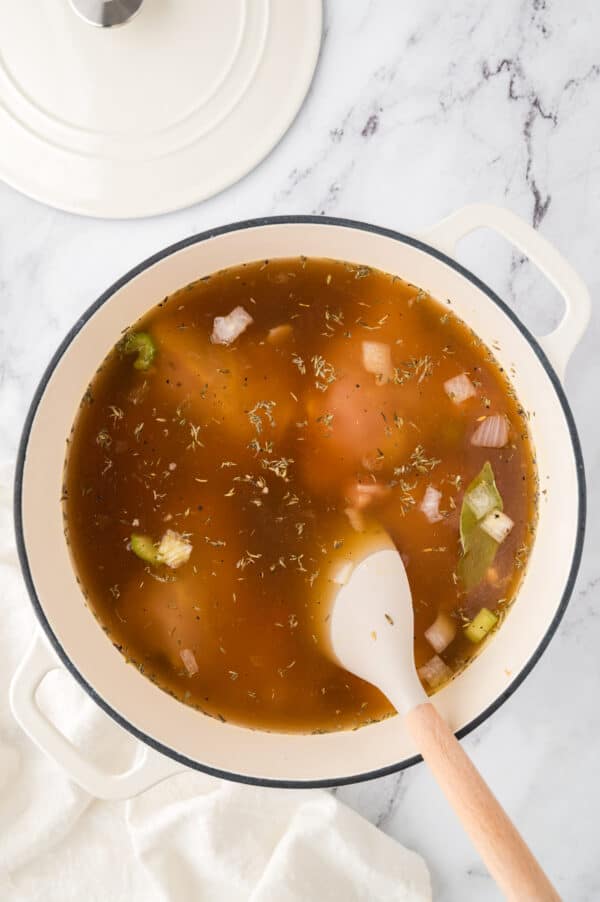 Chicken soup ingredients being stirred together in a large pot.