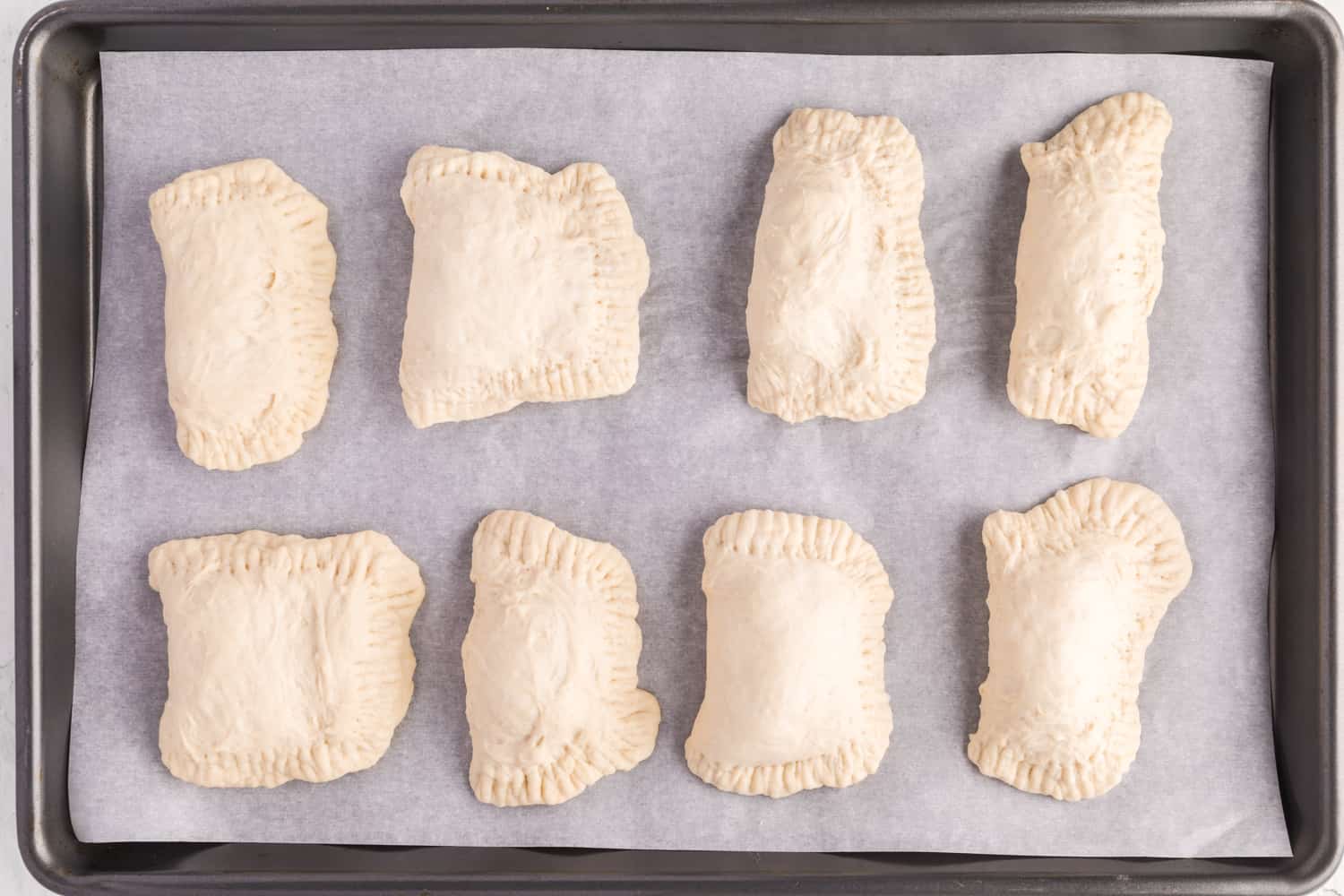 Unbaked hot pockets on a sheet pan.