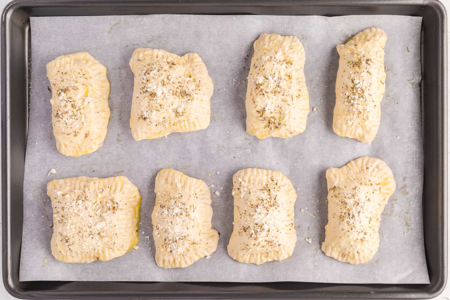 Unbaked pepperoni pizza hot pockets on a sheet pan.