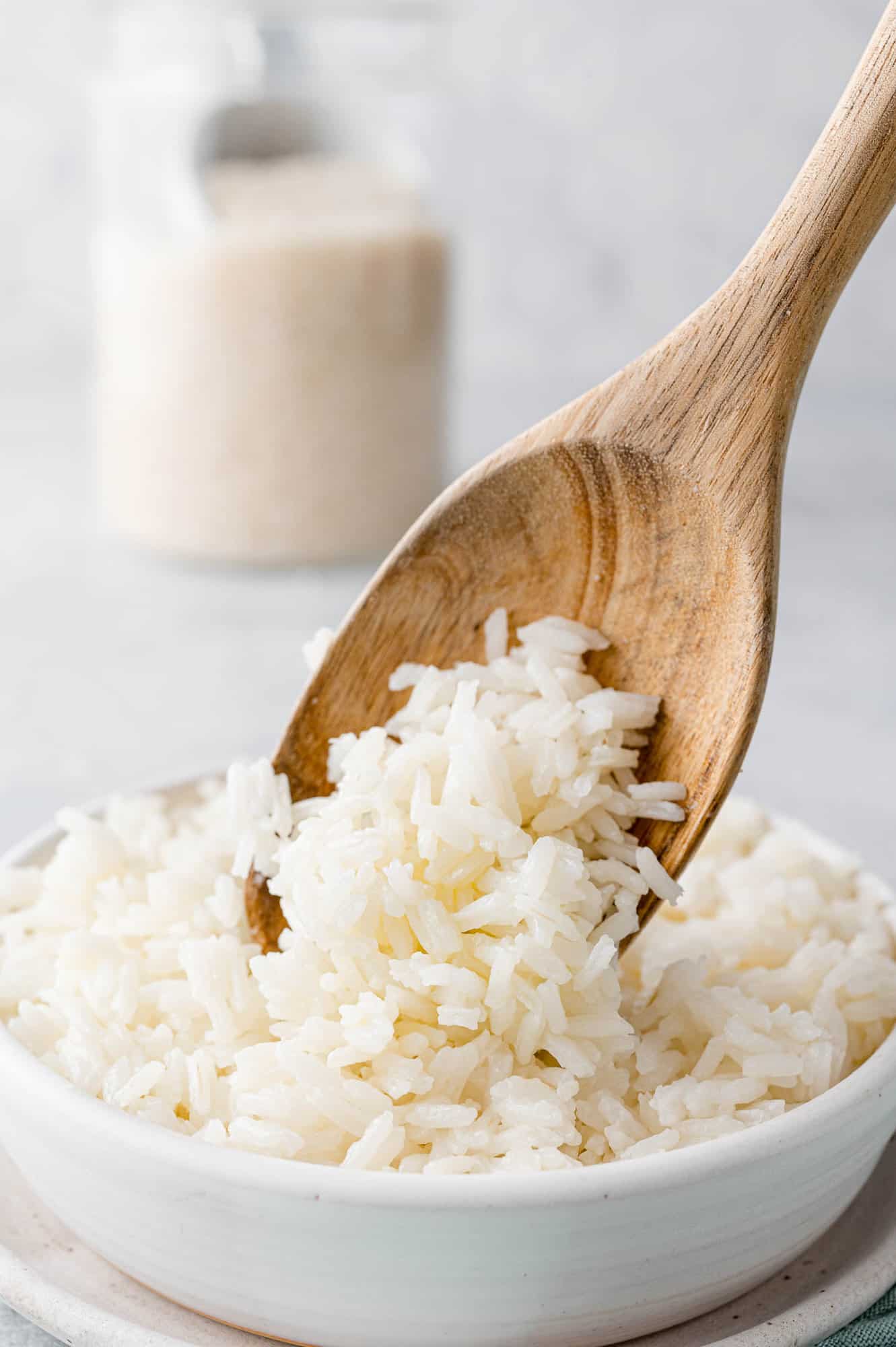 Wooden spoon scooping rice into a white bowl.