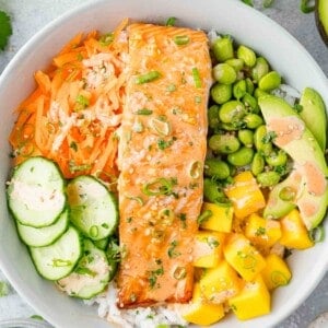 Close up view of salmon bowl, showing salmon and lots of colorful fruits and vegetables.
