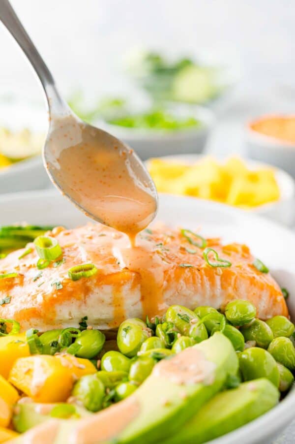 Sauce being added to salmon bowl.