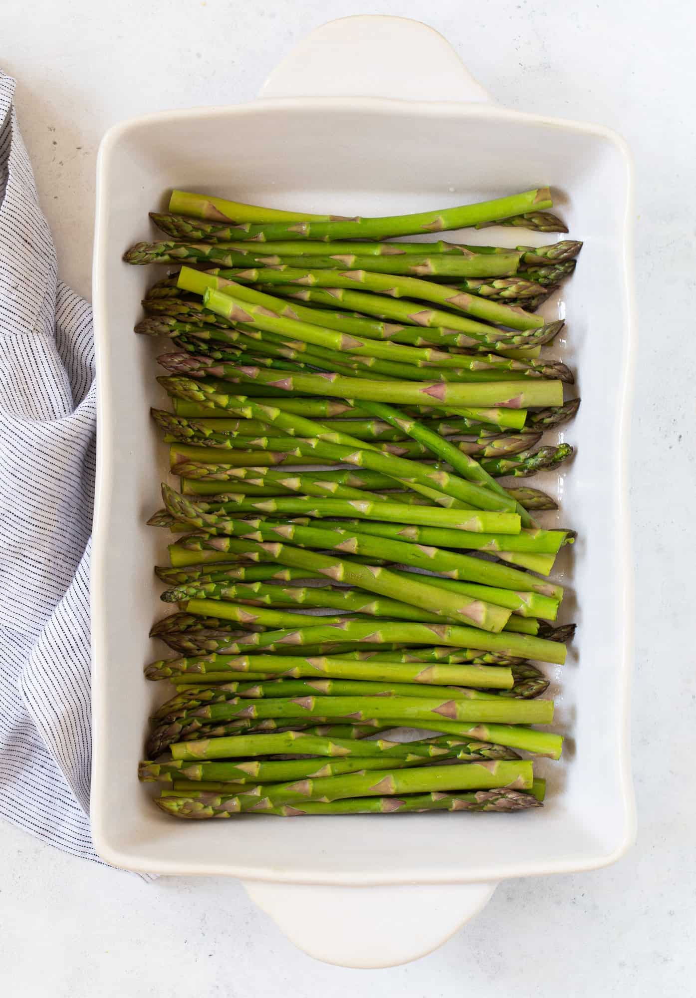 Uncooked asparagus in a baking dish.