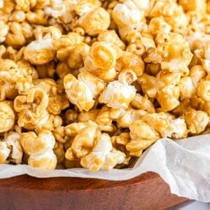 Homemade caramel corn in a parchment paper lined wooden bowl.