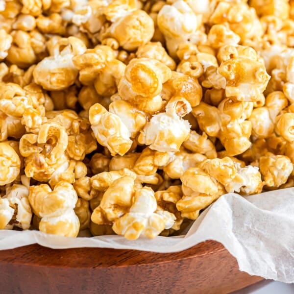 Homemade caramel corn in a parchment paper lined wooden bowl.