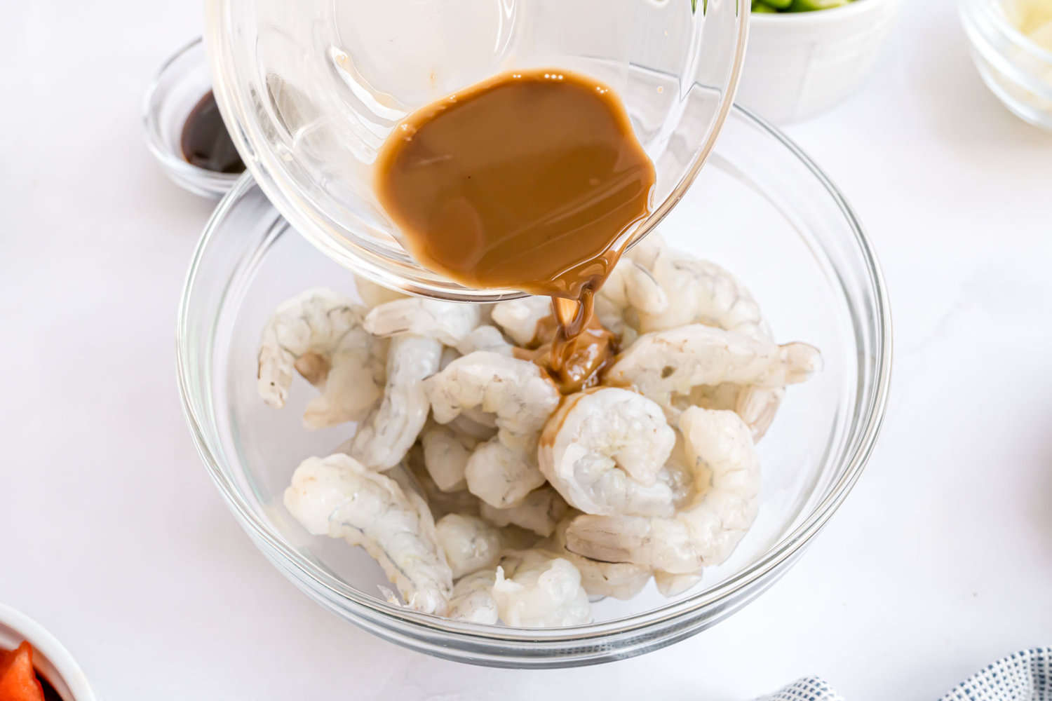 Marinade being poured onto uncooked shrimp.