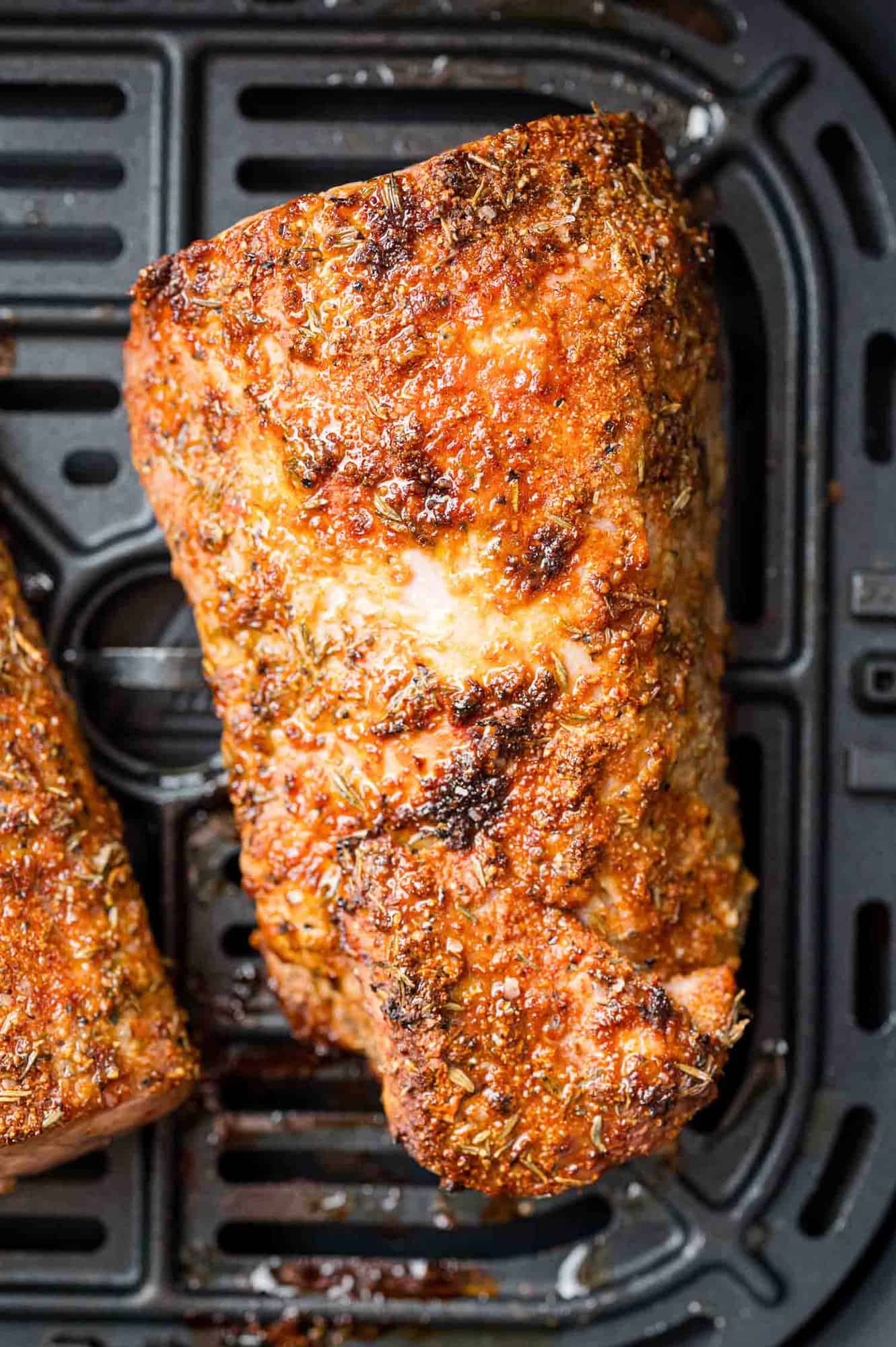 Cooked pork tenderloin in air fryer basket.