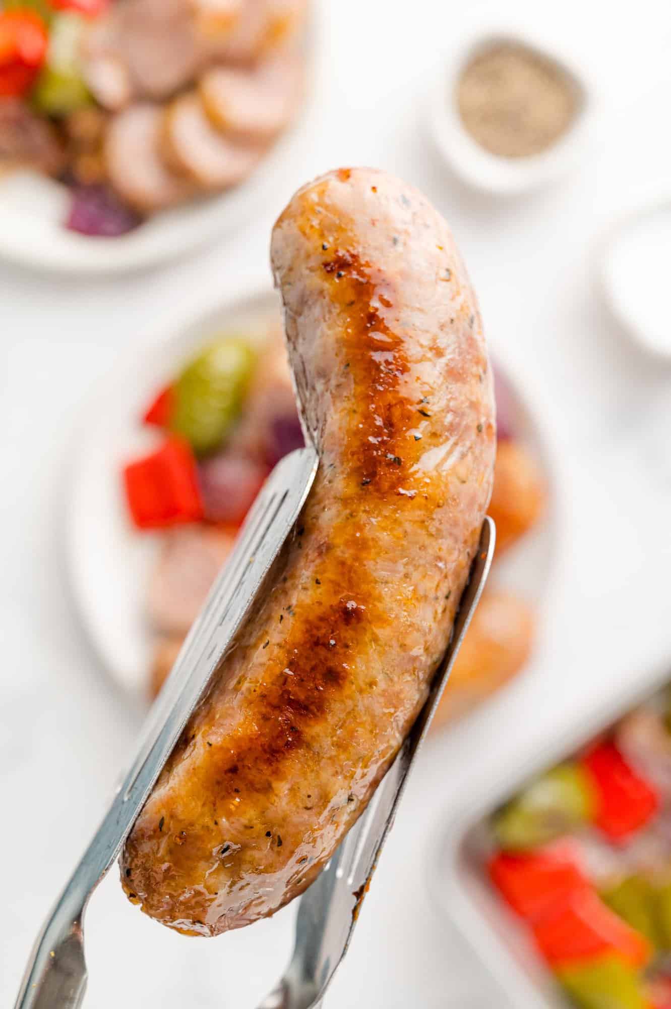 Sausage held between tongs.